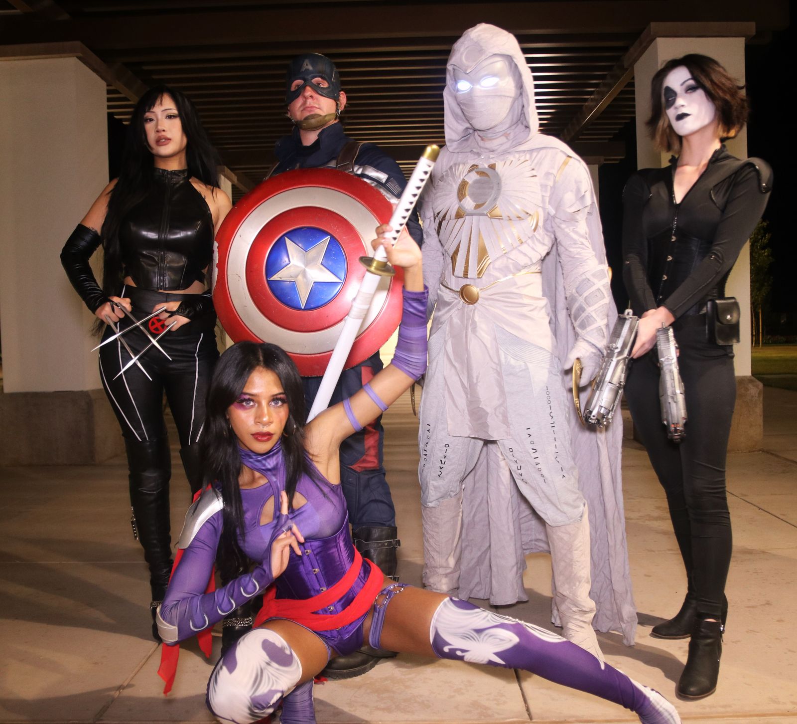 Team of five superhero characters posing together at night