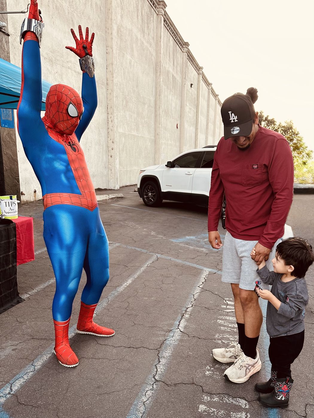 Spider hero celebrating with a toddler and his dad at an event