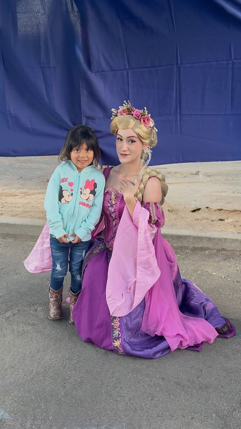 Tower princess character kneeling beside a smiling little girl at a party